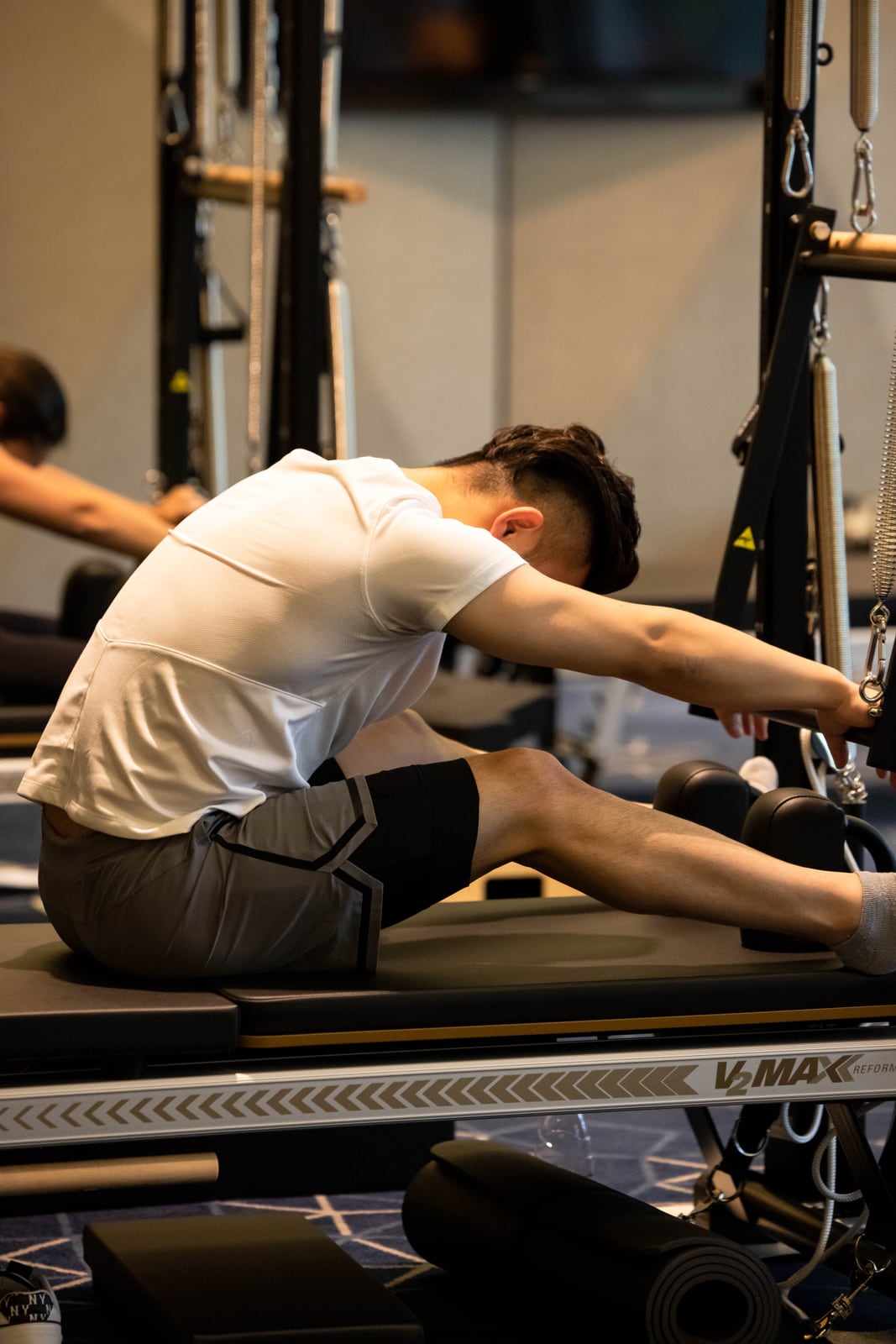 Seated participant reaching forward on a Pilates Reformer